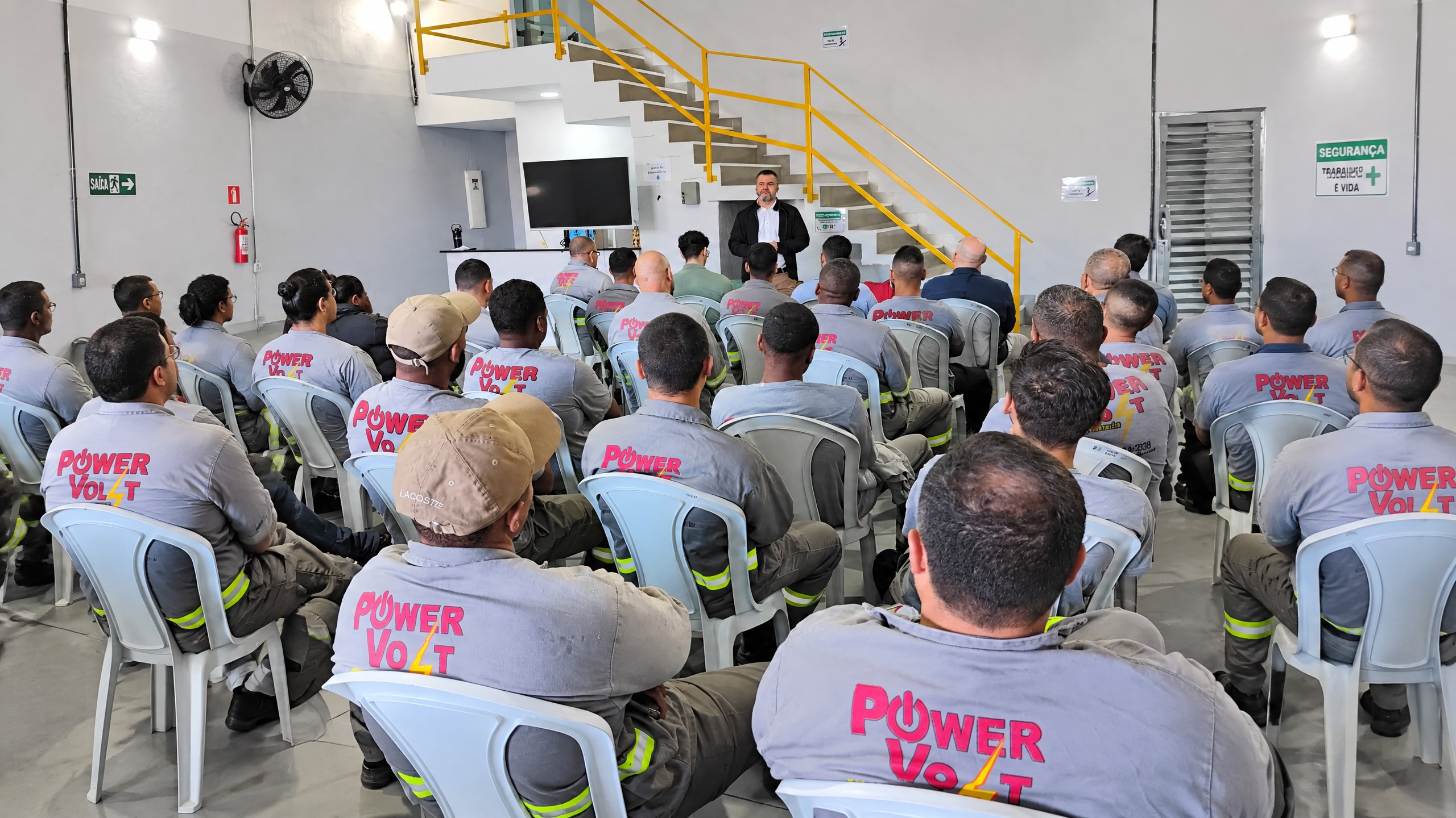 Equipe Power Volt em palestra, uniforme cinza com logo nas costas