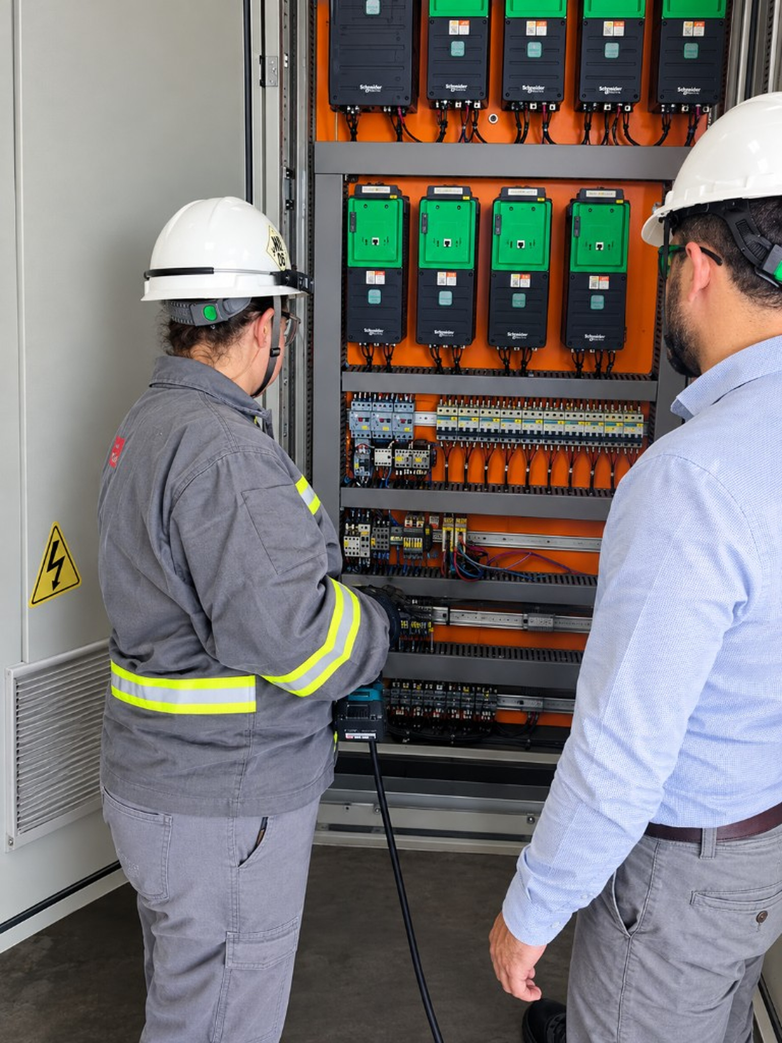 Inspeção de painel Schneider com uniforme e capacete branco